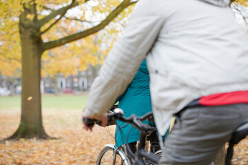 Senior couple bike riding among leaves and trees in autumn park