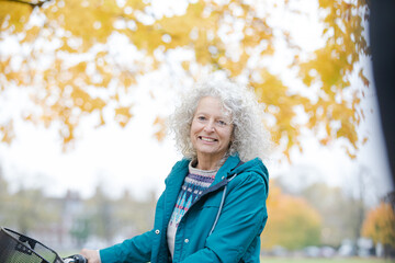 Portrait smiling woman  among leaves and trees in autumn park