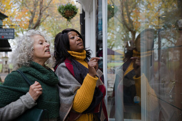 Senior women friends window shopping outside storefront