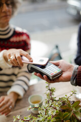 Senior woman paying at cafe with smartphone