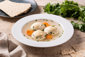 Traditional Jewish matzah ball soup on wooden table	