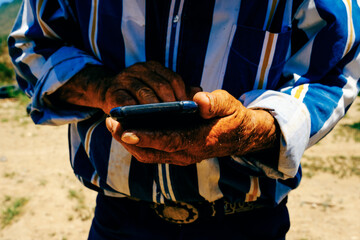 Midsection of senior man holding smartphone on sunny day