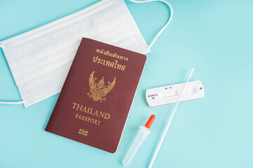 Top view of anti virus mask, passport and rapid antigen test kit on blue background. Global pandemic outbreak.