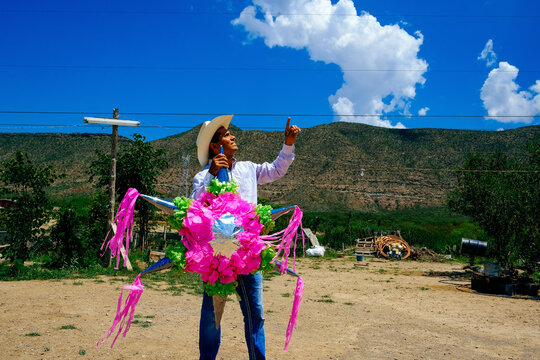 Mature man looking up while holding star shape decoation pinata at field on sunny day