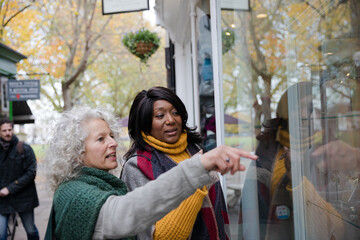 Senior women friends window shopping outside storefront