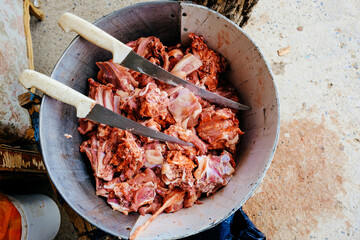 Closeup of fresh raw meat with knives kept in container at farm