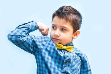 boy shows strength with a gesture. portrait of a beautiful boy on a blue background