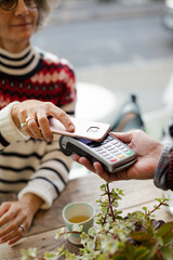 Senior woman paying at cafe with smartphone