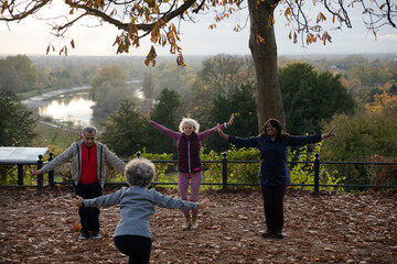 Senior man with active senior women doing exercise at autumn park