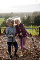 Smiling active senior women friends with walking sticks