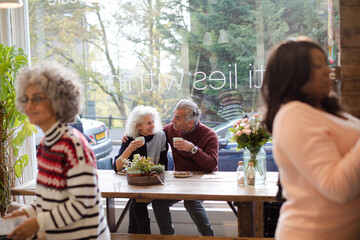 Smiling active senior couple enjoying coffee at  cafe
