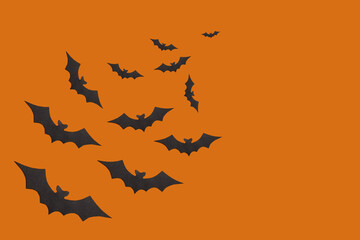 Halloween decorations concept. Black paper bats on orange background. Banner, copy space..