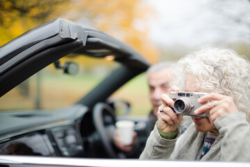 Active senior couple using digital camera in car