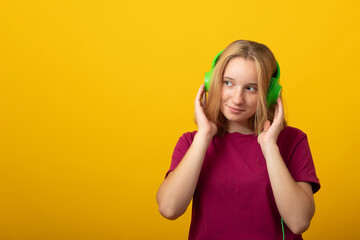 Fototapeta premium Carefree smiling young woman listens music in headphones isolated over vivid yellow background.