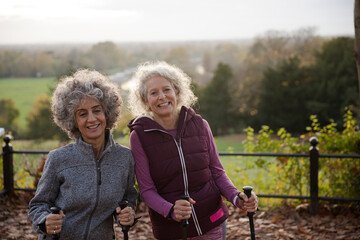 Portrait smiling active senior women friends with walking sticks