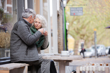 Affectionate senior couple holding hands in autumn cafe