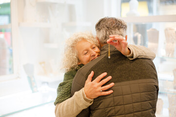 Happy senior woman hugging husband in jewelry store