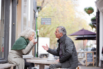 Senior couple drinking coffee at sidewalk cafe