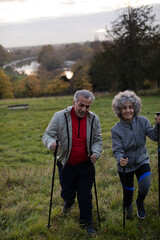 Smiling, affectionate senior couple wih walking sticks