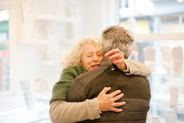 Happy senior woman hugging husband in jewelry store