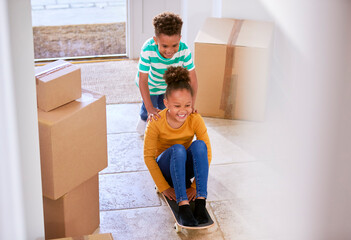 Two Children With Boxes On Moving In Day Playing On Skateboard