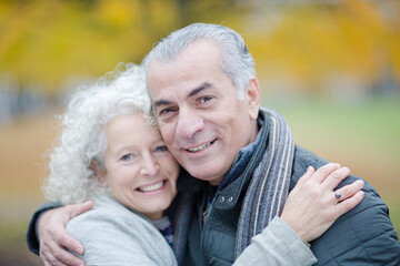 Fototapeta premium Portrait smiling, affectionate senior couple hugging in park