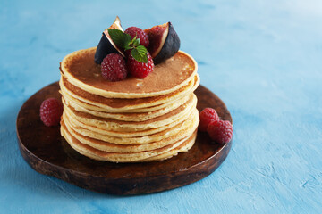 .Pancakes on a blue background, with raspberries, mint and figs