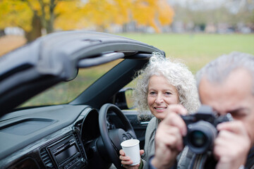 Smiling, affectionate senior couple taking photo from car