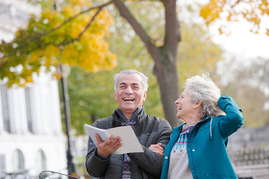Senior couple with bicycles traveling, looking at guidebook along autumn river - Powered by Adobe