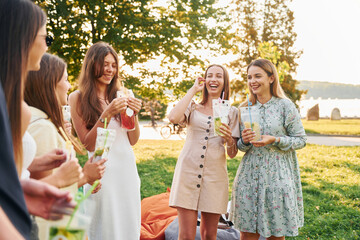 Having a drink. Group of young people have a party in the park at summer daytime