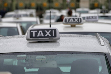 Closeup of the taxi cabs roof signs. Cars parked in rows waiting for customers.