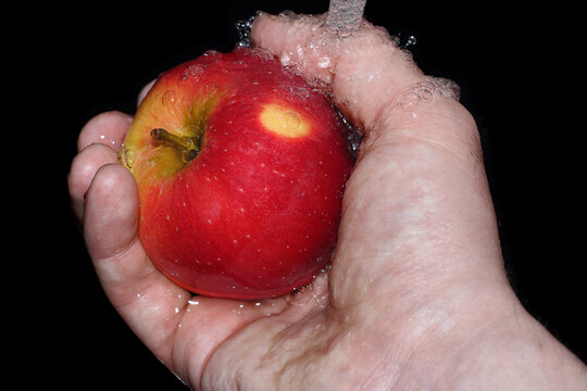 red apple in hand is washed under running water