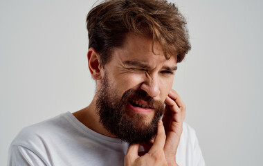 bearded man holding his face toothache