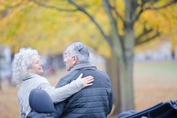 Affectionate, tender senior couple hugging in autumn park near car