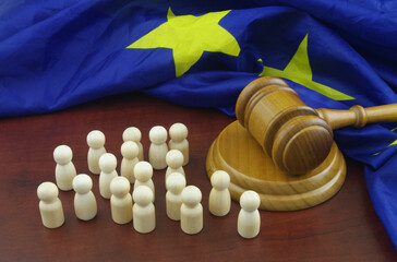 Legal system of European Union concept. Wooden figures of people, EU flag and judge gavel.