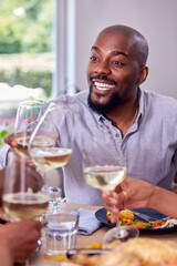 Father Making Toast With Wine As Multi Generation Family Sit Around Table And Enjoy Eating Meal