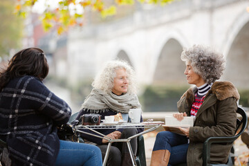 Portrait smiling, happy active senior women friends drinking coffee at autumn park cafe