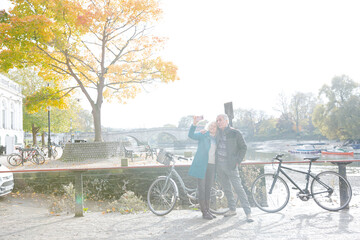 Obraz premium Senior couple with bicycles taking selfie at autumn river