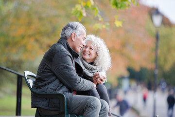Active senior couple talking, enjoying coffee at autumn park cafe
