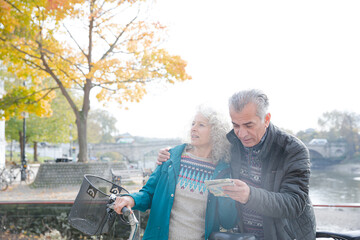 Adventurous senior couple with bicycles looking at map