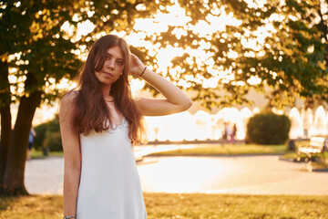 Posing for a camera. Woman standing in the autumn park. Beautiful sunshine