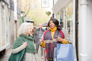 Senior women friends window shopping outside storefront