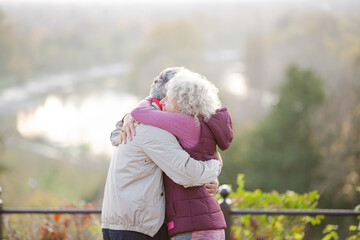 Affectionate active senior couple hugging at park pond