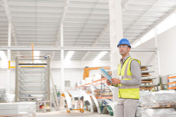 Male supervisor with paperwork walking in factory