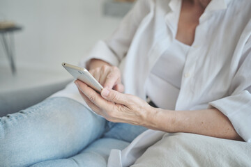 Using mobile phone applications, close up on a mature elderly woman. chatting on social media or purchasing online, smartphone scrolling social media swiping scrolling, elderly entrepreneur r