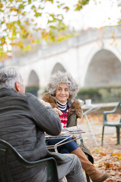 Active Senior Couple Talking, Enjoying Coffee At Autumn Park Cafe