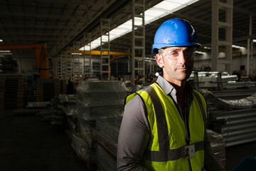 Portrait serious male worker in protective eyewear and hard-hat in factory