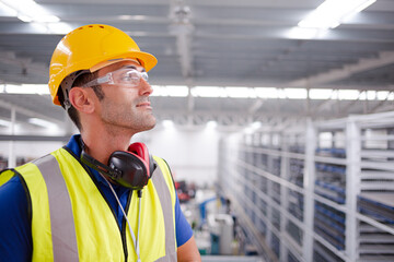 Portrait serious male worker in protective eyewear and hard-hat in factory