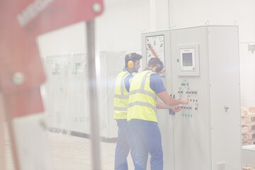 Engineers working at control panel in factory