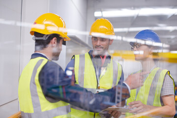 Supervisors and worker with clipboard talking in factory